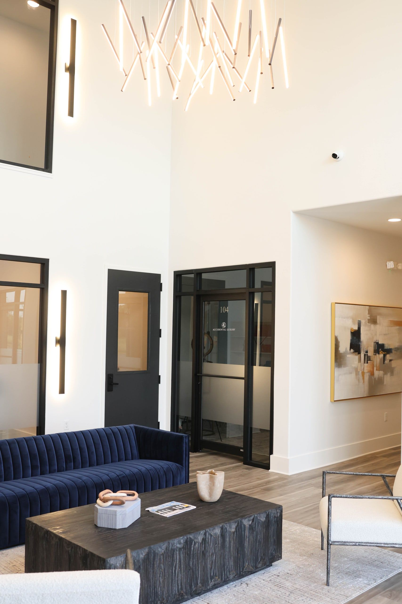 Double-height lobby at The W Office Suites Double-height office lobby at The W Office Suites with a modern linear chandelier and black steel-and-glass suite doors