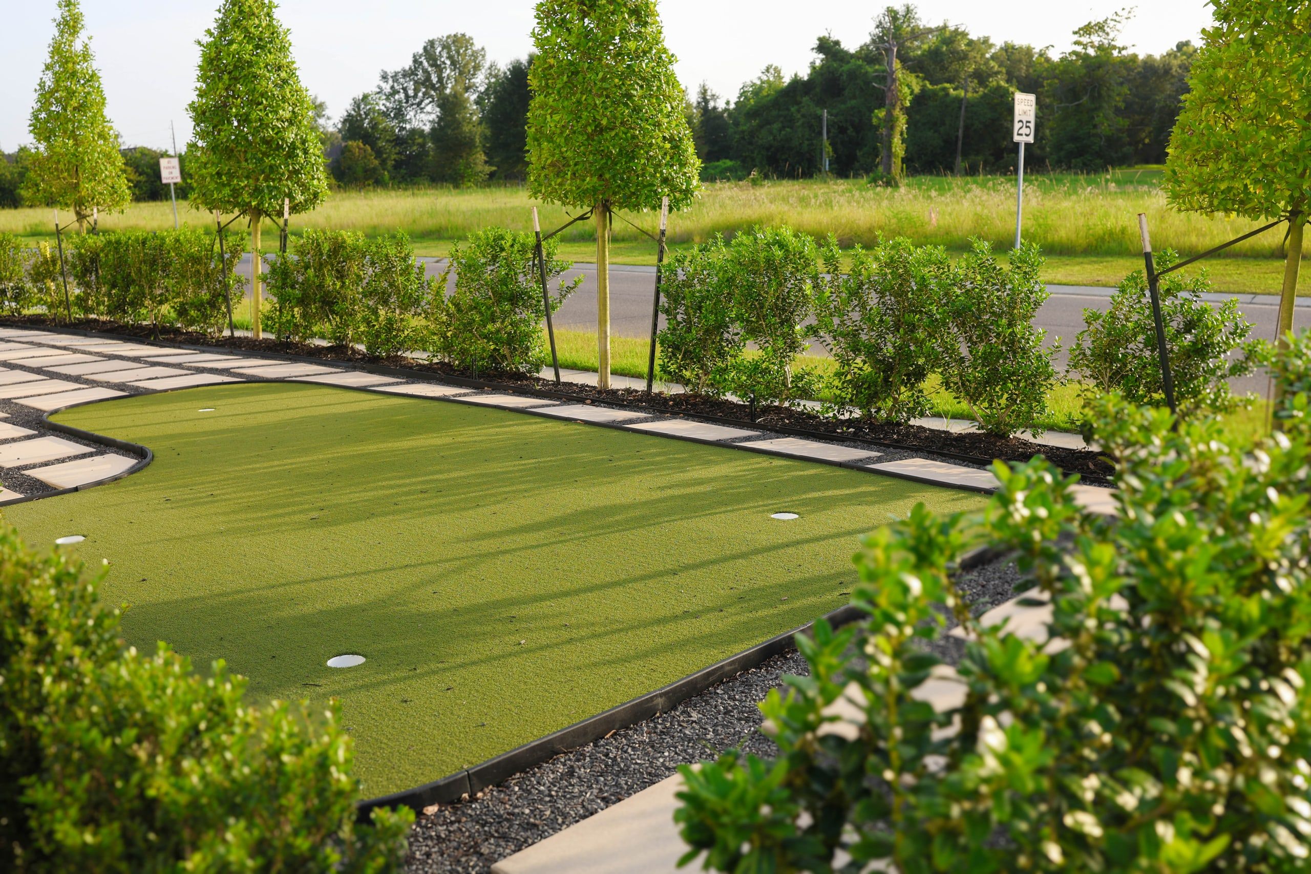 Landscaped courtyard with a private putting green and paver walkway at The W Office Suites in Prairieville, LA