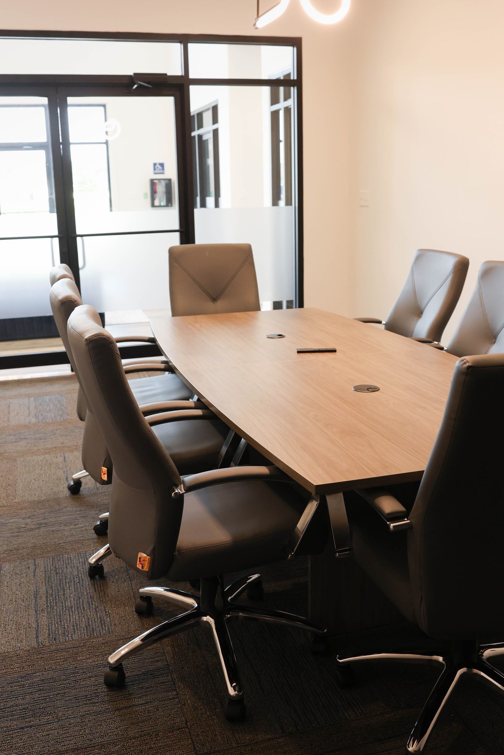 Shared conference room for tenants at The W Office Suites, with a long wood boardroom table and gray executive chairs